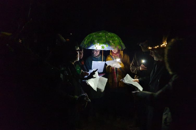 Welly Wassailers sing from the shelter of an umbrella