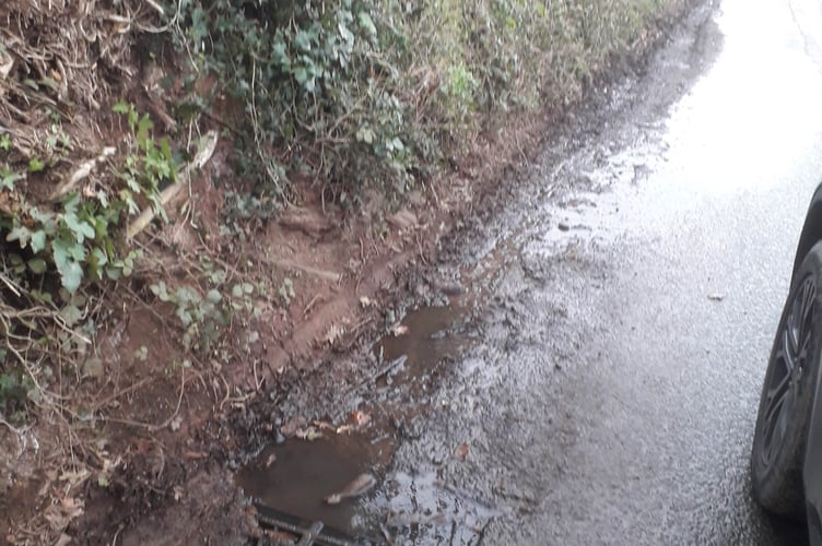 Water can be seen pouring from a blocked drain in Burchills Hill, Wellington, and flowing downhill where it froze into sheet ice, with the crash scene just visible.