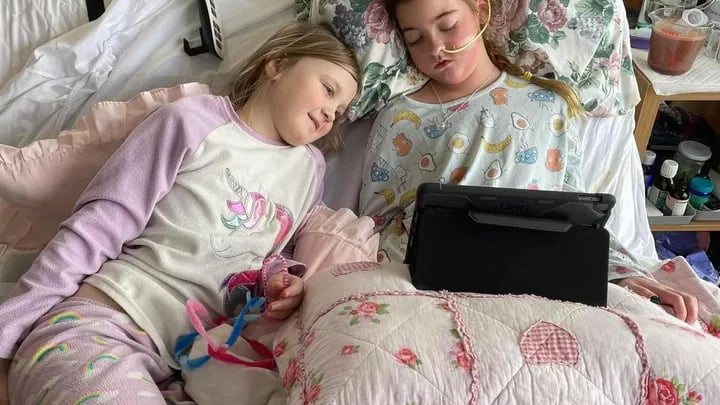 Harper Pumfrey in her bed with her sister.