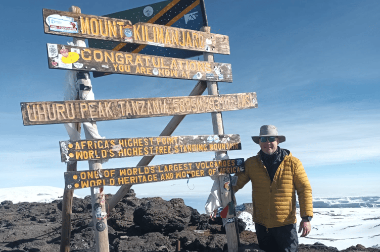 Tim Sandy standing by the mount kilimanjaro sign